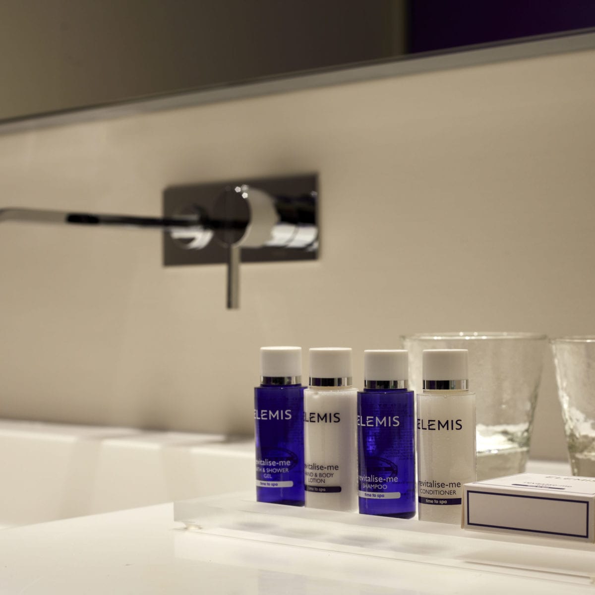 Blue and White amenities on the white bathroom with 2 glasses in the background