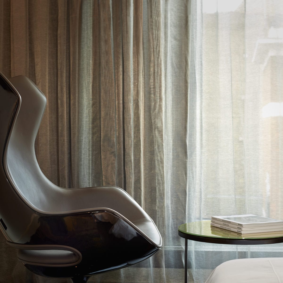 The brown armchair of a superior twin room in front of a window.