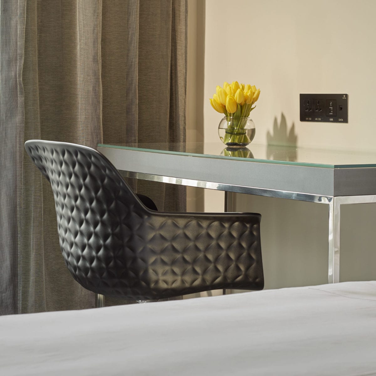 Shot of a brown chair and desk with yellow flowers on top