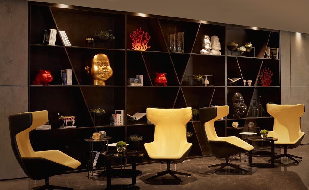 Four yellow and black chairs in front of a black bookcase with an assortment of different coloured items.