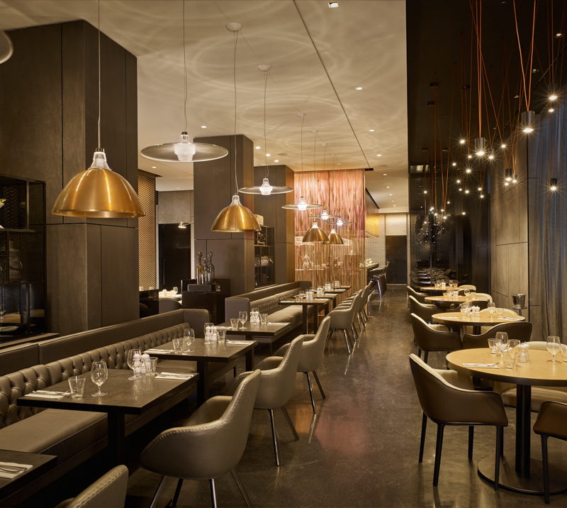 Long rows of wooden tables with gold lights hanging from the ceiling