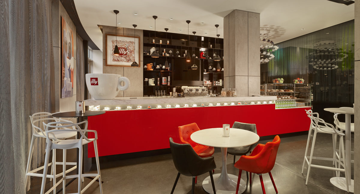 the bright red counter of Illy Cafe with a massive Illy cup on the counter