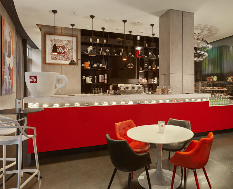 the bright red counter of Illy Cafe with a massive Illy cup on the counter