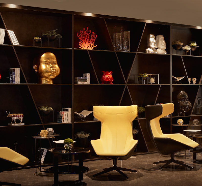 Yellow chairs and tables in the lounge area in front of a black bookshelf
