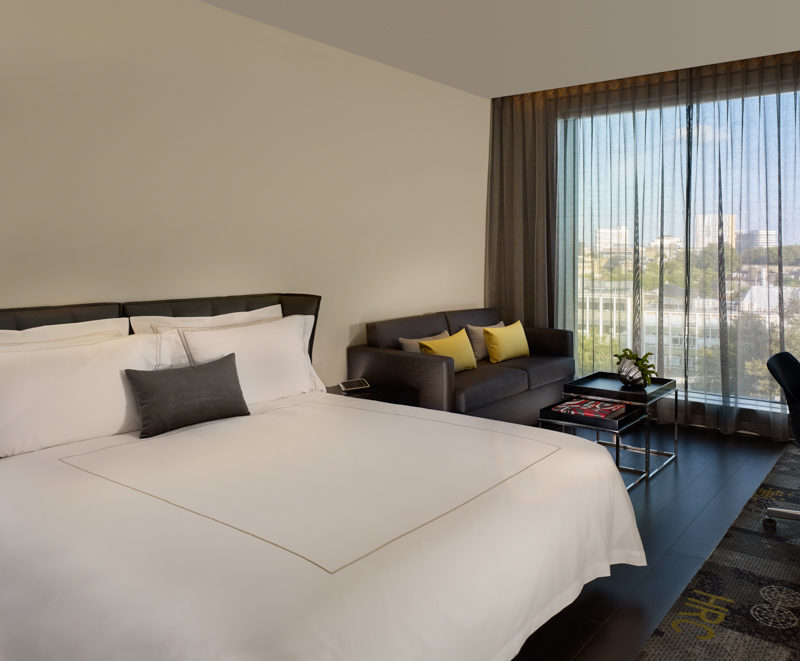 Bright white twin beds in front of a sofa with yellow pillows