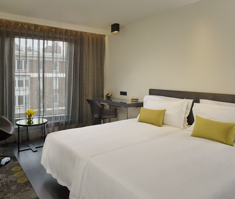 Twin beds with bright white covers, each with a gold pillow on top