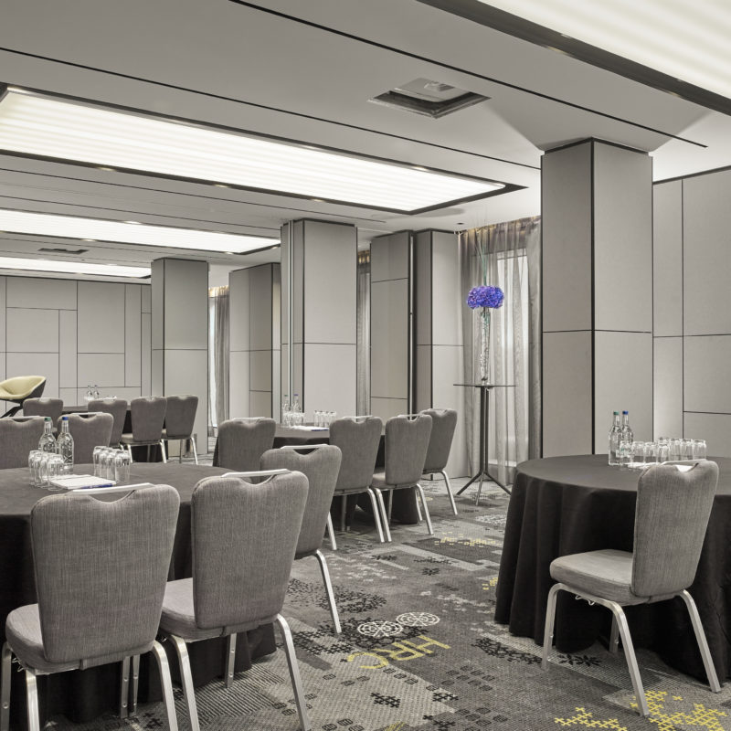 Circular tables with black tablecloths over the top of them surrounded by grey chairs