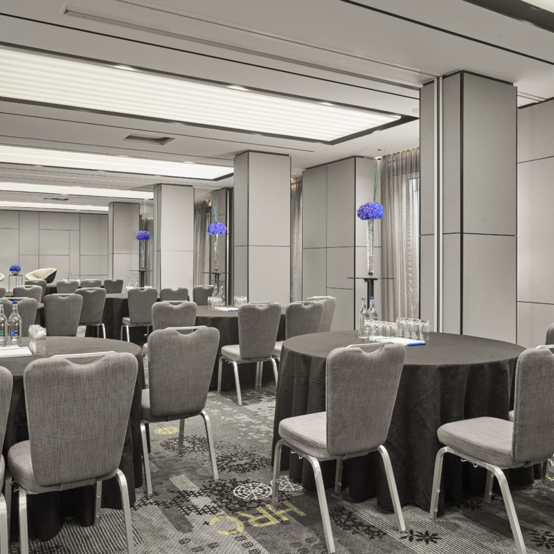 Circular tables with black tablecloths over the top of them surrounded by grey chairs