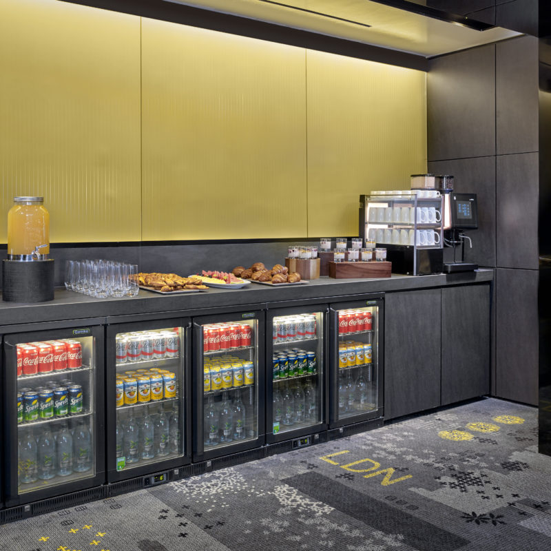 A collection of red, green and yellow soft drinks in fridges below a yellow backdrop