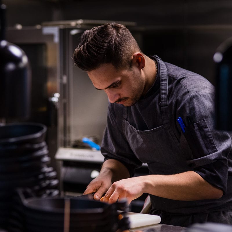 A chef from Florentine Restaurant in a navy blue apron preparing food