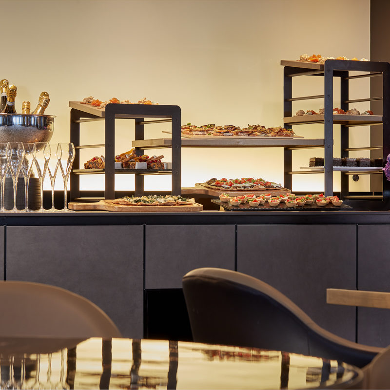 Trays full of golden brown pastries next to a ice bowl of gold topped champagne