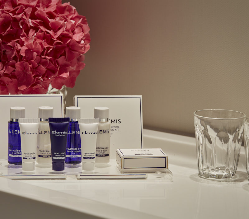 A display of blue and white bathroom amenities in front of a pink flower display
