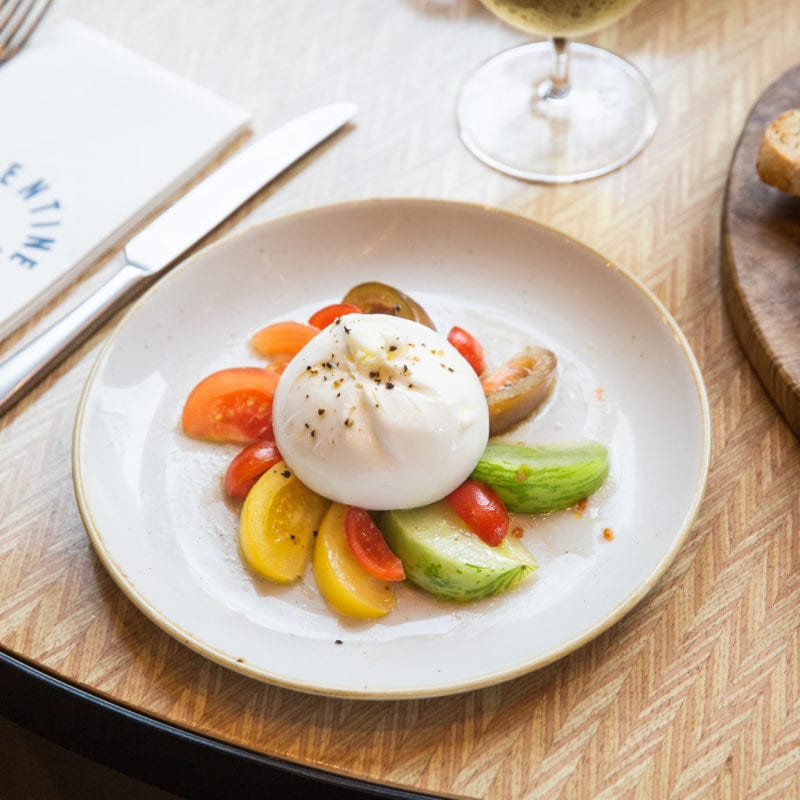 Freshly made Burrata on a multi-coloured bed of vegetables