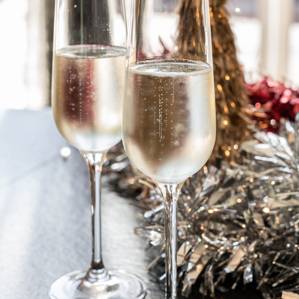 Two Prosecco filled glasses in front of Christmas decorations