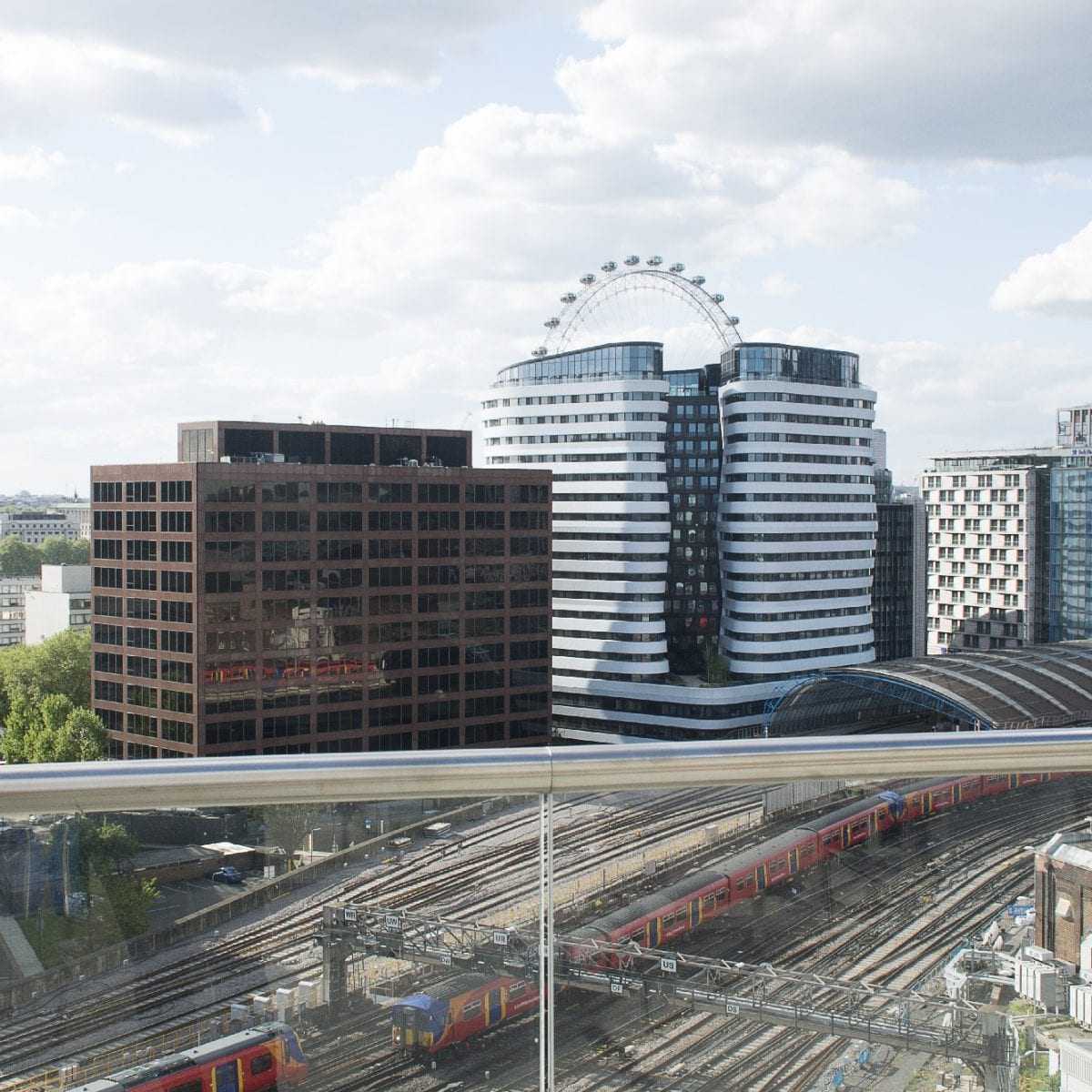 A bright shot of the 12th floor terrace with a blue sky and red trains going underneath